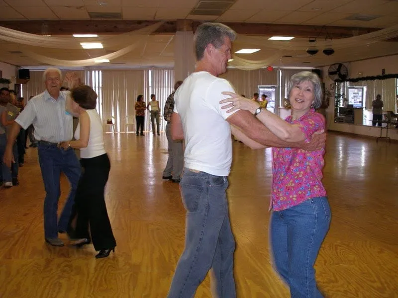 A couple dancing in the studio while a class practises behind them